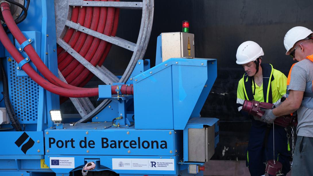 dos operarios conectan un barco al ops de la terminal best.
